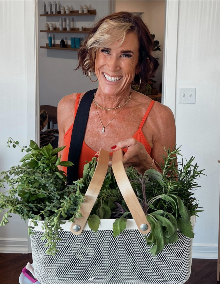 Sandi Krakowski, founder of A Real Change Health, holding a basket of fresh herbs